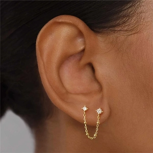 Macro shot of gold tassel chain earrings connecting two zircon studs for a layered look