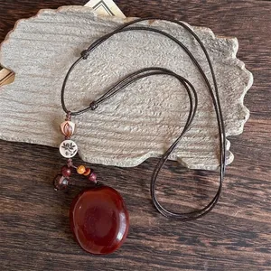 Detailed view of an ethnic resin pendant with lotus ceramic beads and leather cord