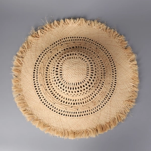 Detail showing natural beige raffia hat with hollow weave patterns and fringe brim edge