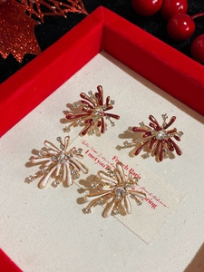 Detail of fireworks-shaped rhinestone stud earrings in red and white on a festive gift box