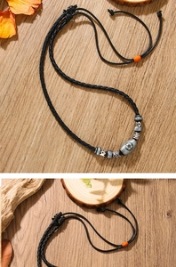 Detail of football pendant necklace with ceramic beads on a black braided cord strap