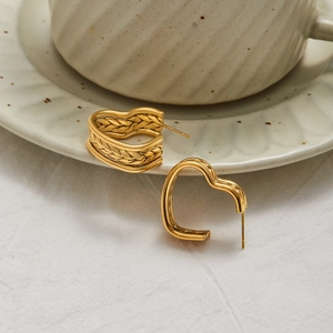 Detail of 18K gold stainless steel heart earrings with woven texture on white fabric