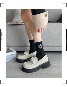 Detail of black ribbed mid-calf socks with white camellia flower and platform loafers