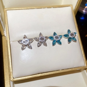 Detail of silver stud earrings featuring star-shaped clear and blue zircon crystals