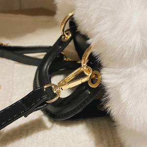 Detail of white faux fur texture with black leather handle and gold metal hardware