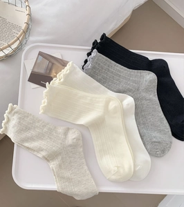 Detail of ribbed cotton socks with elegant ruffled edges in neutral solid colors