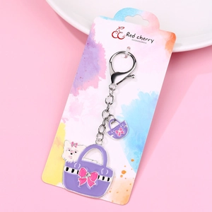 Detail of purple handbag keychain featuring a white puppy and pink bow on a display card