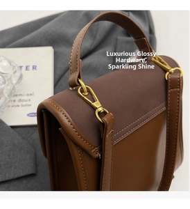 Detail view of the premium brown leather handbag featuring glossy light gold hardware hooks