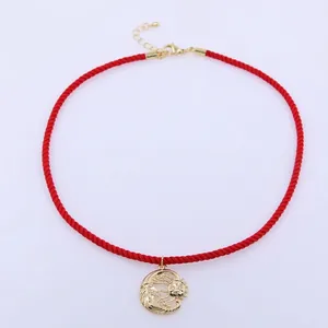 Dettaglio di una collana in corda intrecciata rossa con ciondolo dorato sole e luna