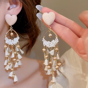 Detail of elegant beaded heart earrings with gold water-drop frames and long silky tassels