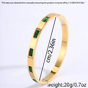Detailed view of gold titanium bangle with five emerald green rectangular zircons
