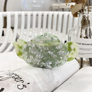 Detail of teapot-shaped hair claw clip with green and white marble acetate texture