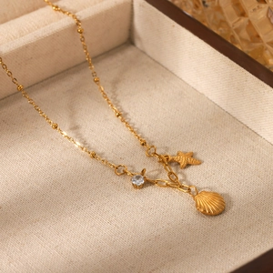 Detailed shot of starfish and shell pendants with zircon on a gold beaded chain