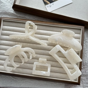 Close-up of cream marble hair claw clips set elegantly arranged on a beige velvet tray