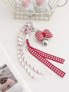 Detail van sleutelhanger met rood-witte ruitjesstrik, zilveren hartje en kwastje