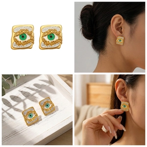 Macro detail of gold plated square evil eye earrings with green enamel and crystal accents
