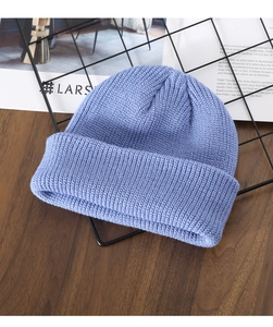 Blue-purple thick knit beanie cap on a dark wood table with a minimalist background