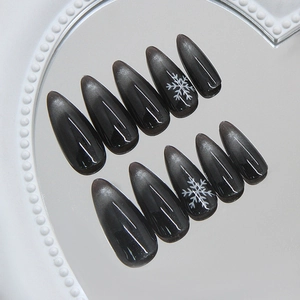 Cat eye press on nails in dark black with snowflake art and almond shape on mirror tray