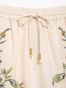 Detailed macro of embroidered floral patterns and beaded drawstrings on knit shorts