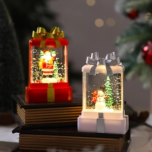 Detail of Christmas lantern with Santa and Snowman figures on vintage books with bokeh lights
