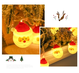 Detail of warm yellow LED Christmas lights with Santa Claus pendants on pine branches
