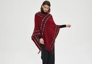 Close-up of red knitted poncho featuring ethnic geometric patterns and long fringes