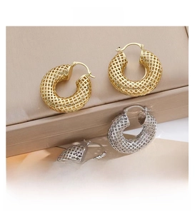 Close-up of gold and silver chunky hoop earrings with intricate mesh texture design