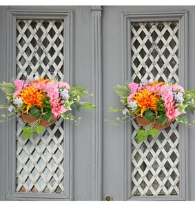 Detail of hanging baskets with orange daisies and greenery on a vintage door