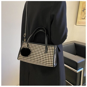 Chic black and white houndstooth handbag with black fur pompom charm and shoulder strap