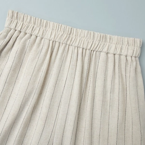 Close-up of elastic waistband detail on beige striped linen trousers with fine texture