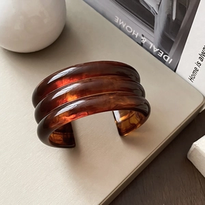 Macro detail of amber resin cuff bracelet with triple layered geometric ribbed texture