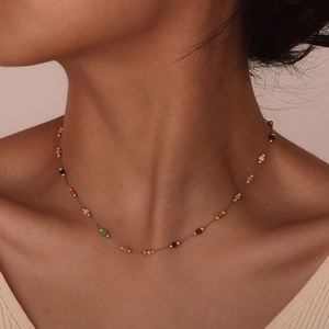 Detailed close-up of a colorful natural stone bead necklace on a model's collarbone