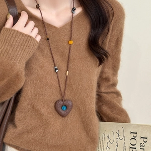 Ethnic heart pendant necklace with brown beads on brown V-neck knitted sweater
