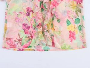 Close-up of pink floral poplin shirt with tiered ruffles and golden button details