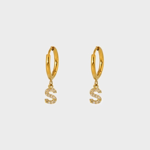 Detailed close-up of a gold-plated hoop earring featuring a sparkling zircon-set S pendant