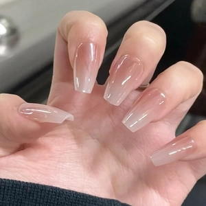 Faux ongles ballerine longs dégradés rose et crème effet brillant portés sur mains