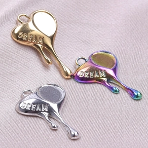 Macro shot of three melting heart DREAM pendants in gold, silver, and rainbow steel