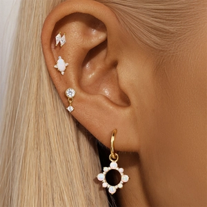 Close-up of gold s925 silver stud earrings with white opal and clear zircon on a model