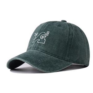 Close-up of white palm tree embroidery on a dark green washed distressed baseball cap