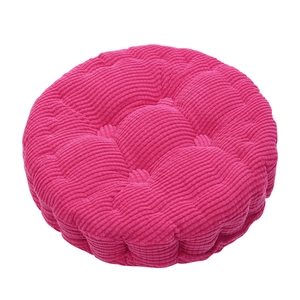 Close-up of thick round rose red corduroy cushion with five-point tufted stitching detail
