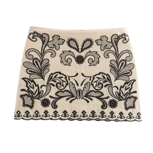Beige cotton-linen mini skirt with black floral embroidery on a white background