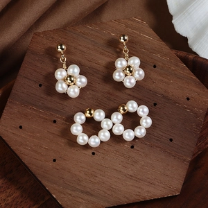 Floral freshwater pearl earrings set with gold-plated finish on hexagonal wood tray
