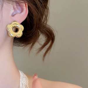 Gros plan d'une boucle d'oreille fleur dorée au fini métallique sur un mannequin