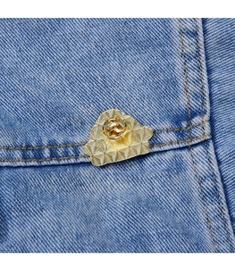 Vue détaillée d'un badge en métal doré avec texture quadrillée sur tissu denim bleu