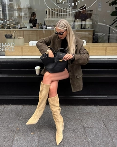 Détails d'une veste en daim marron avec des bottes beiges et un sac à main noir chic