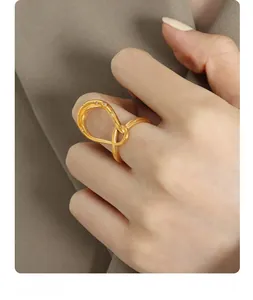 Close-up of golden wavy intertwined ring with white zircon stones on model finger