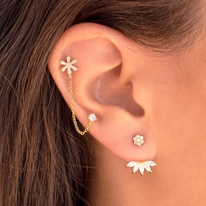 Elegant gold flower zircon stud earrings with chain link for double piercings on model