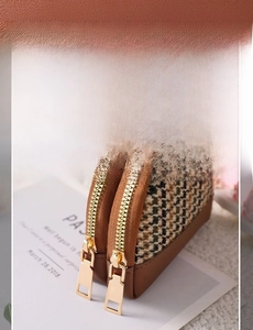Detail of canvas coin purse showing double gold zippers and houndstooth pattern fabric