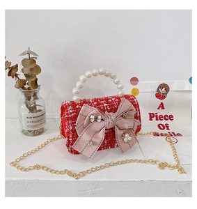 Detailed macro view of a red tweed kids purse with pearl handle and a large pink bow