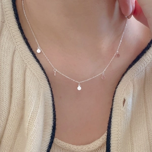 Silver minimalist necklace with tiny round pendants worn on neck with beige sweater